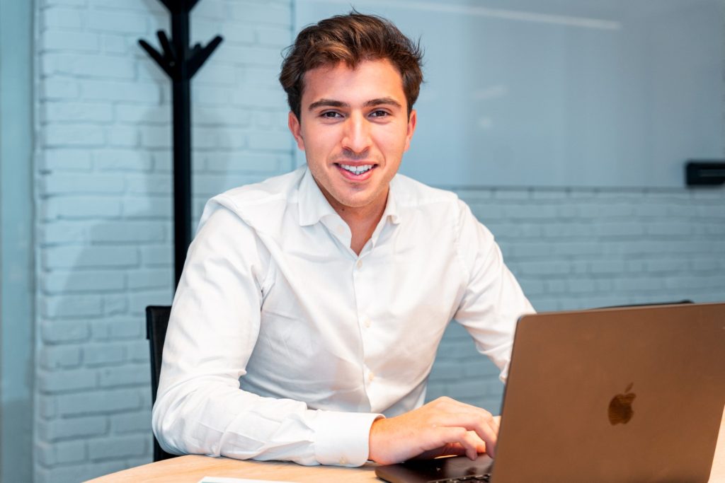 Eigenaar van JLM Agency in kantooromgeving met laptop, beschikbaar voor vragen over bedrijfsfotografie en marketingdiensten."